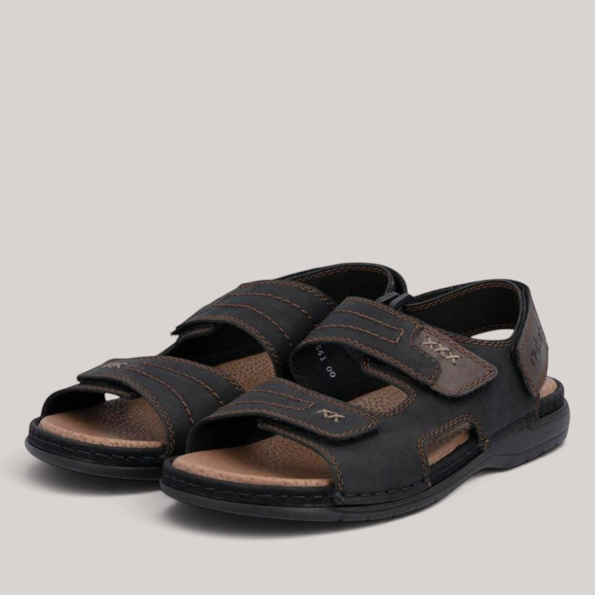 Grundy's Shoes Rieker 25561-00 black leather sandals with three adjustable Velcro straps and a cushioned insole.