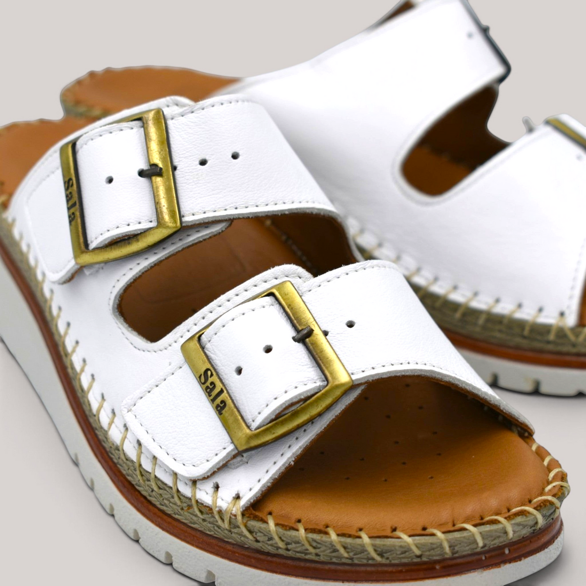 Grundy's Shoes Sala Oasis white leather sandals with adjustable straps, brass buckles, and cushioned platform sole.