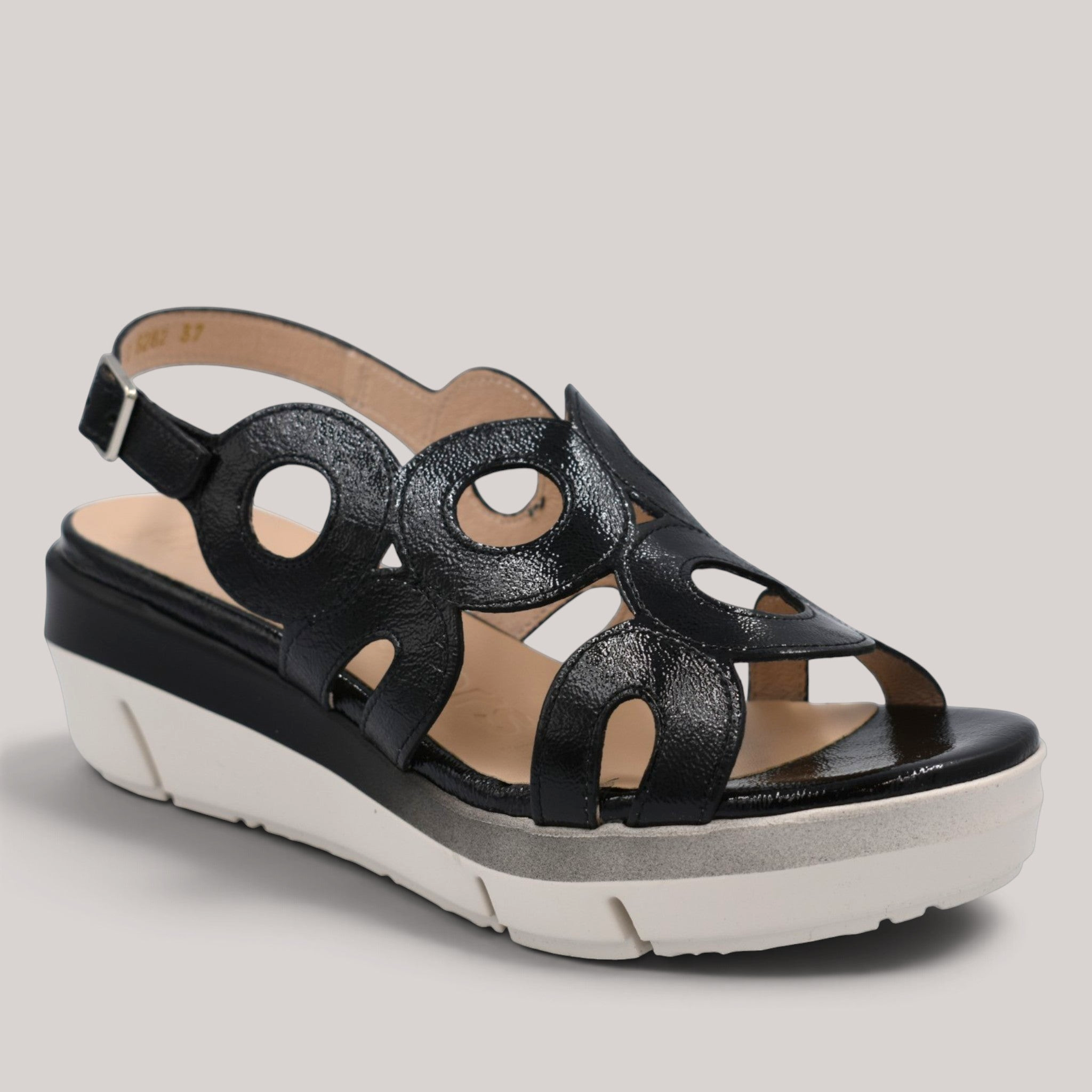 Grundy's Shoes Wonders 8282 black patent leather wedge sandals with circular cutouts and adjustable buckle closure.