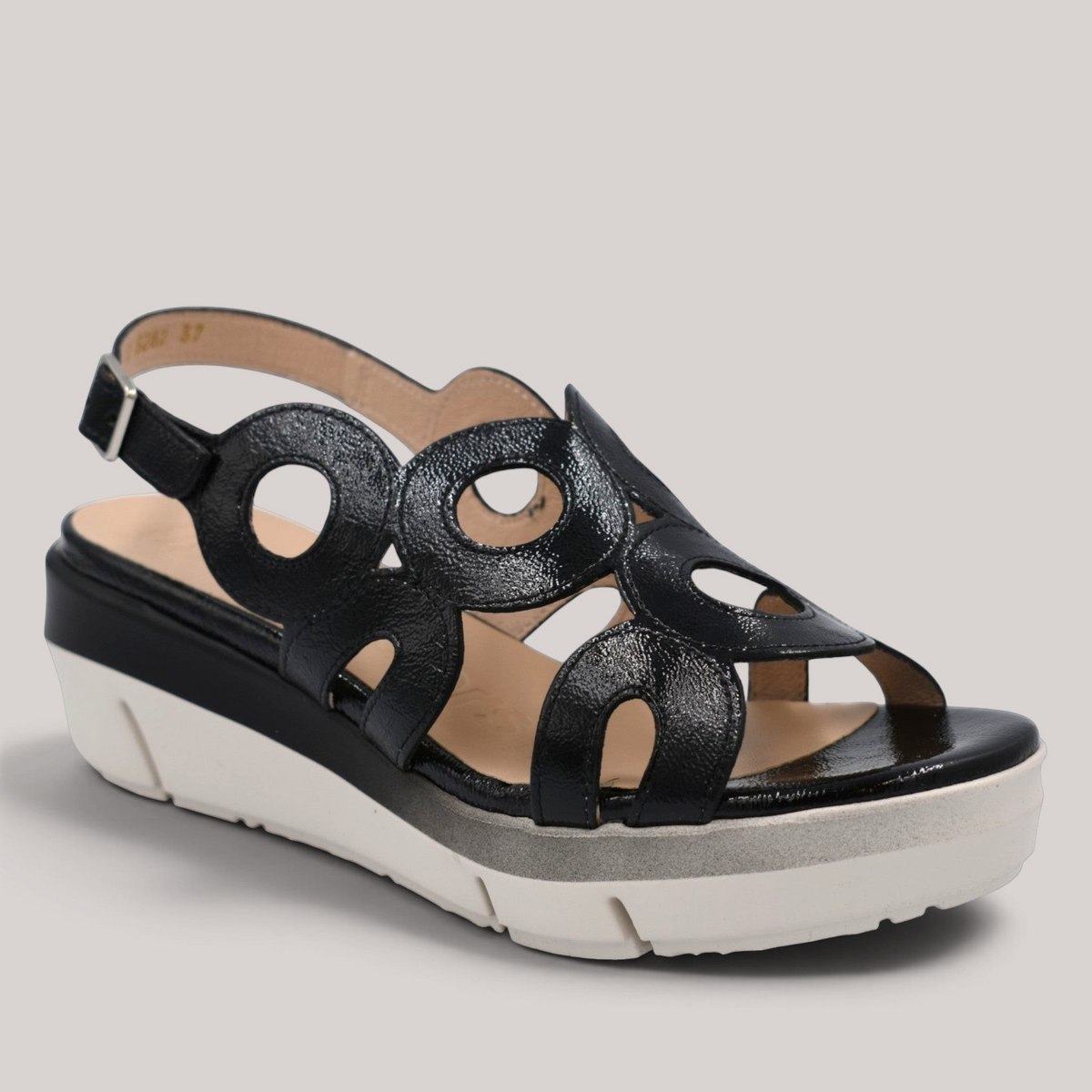 Grundy's Shoes Wonders 8282 black patent leather wedge sandals with circular cutouts and adjustable buckle closure.