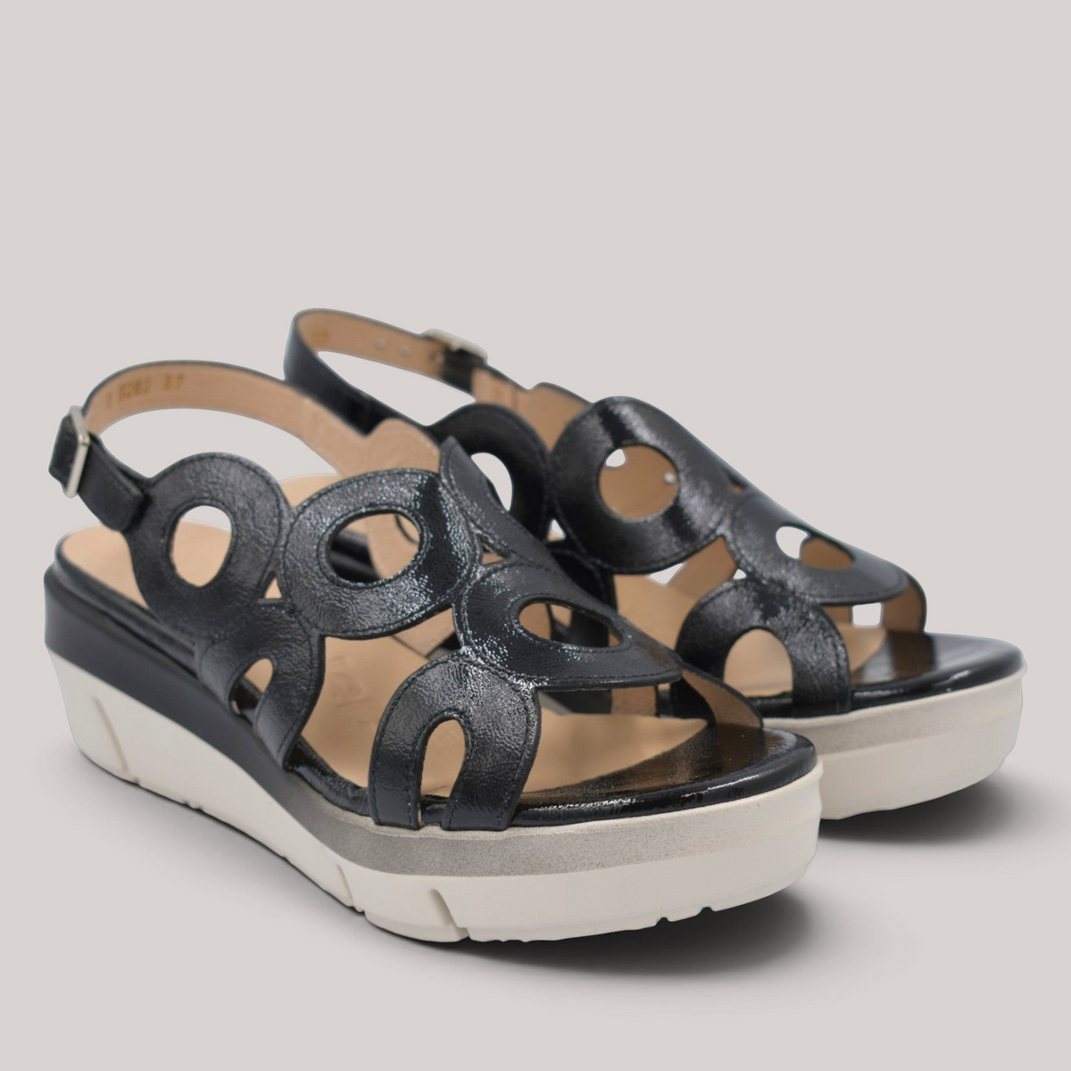 Grundy's Shoes Wonders 8282 black patent leather wedge sandals with circular cutouts and adjustable buckle closure.